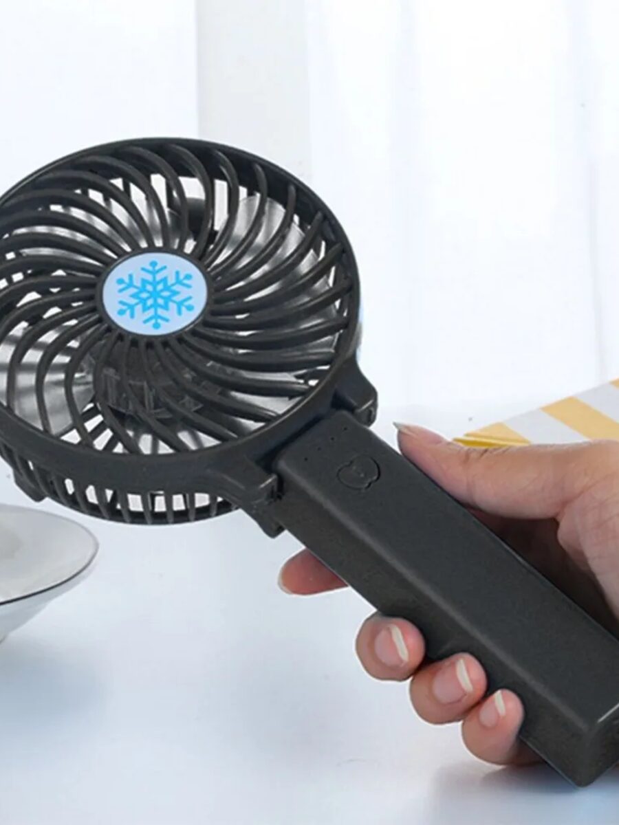 A portable handheld fan held in one hand